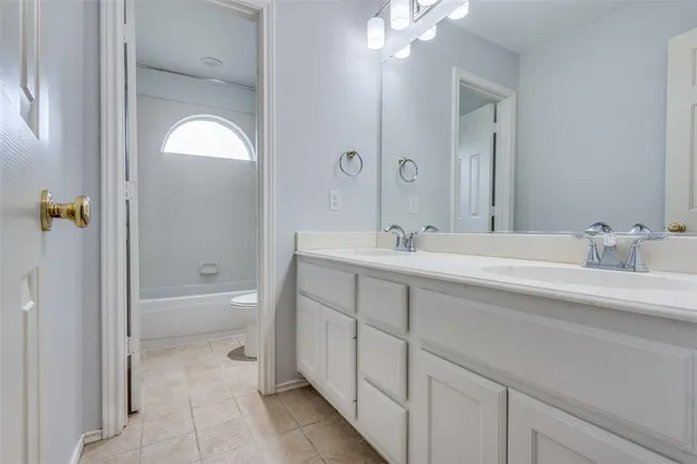 a spacious bathroom with a double vanity sink a toilet and shower