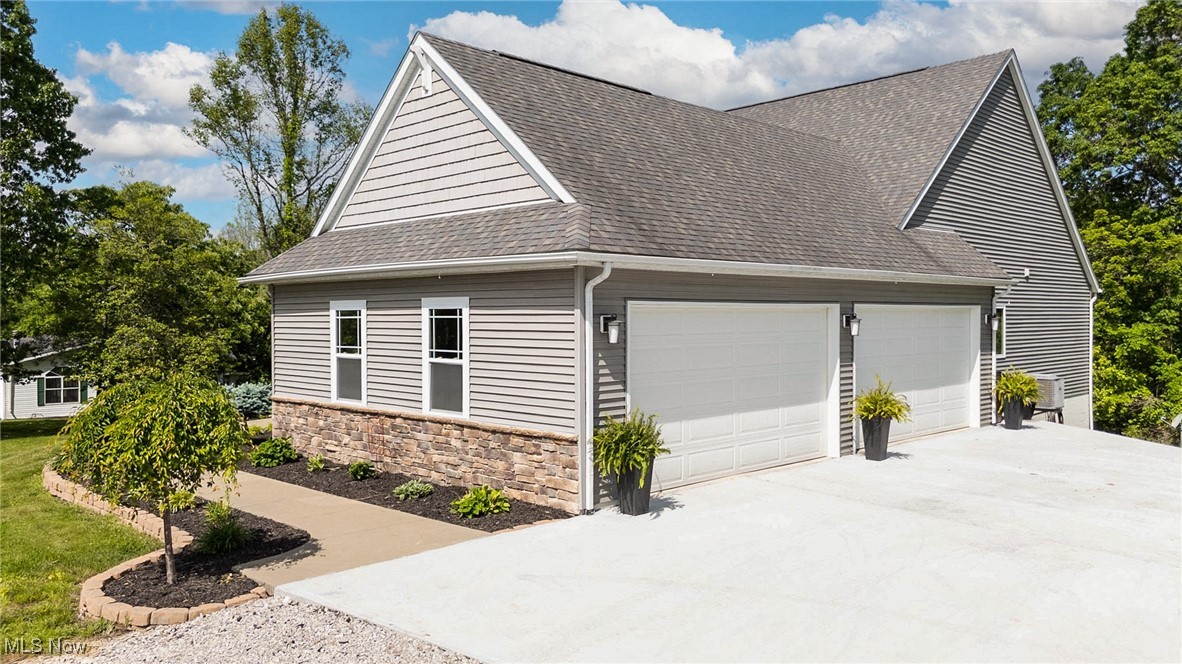 2851 Barnett Ridge Road Fleming, OH 45729 - Photo 4 of 40 View of property exterior with roof with shingles, concrete driveway, an attached four car garage, and stone siding