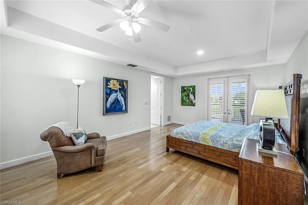 510 Avellino Isles Circle, Unit 2202 Naples, FL 34119 - Photo 13 of 35 a bedroom with a bed and wooden floor