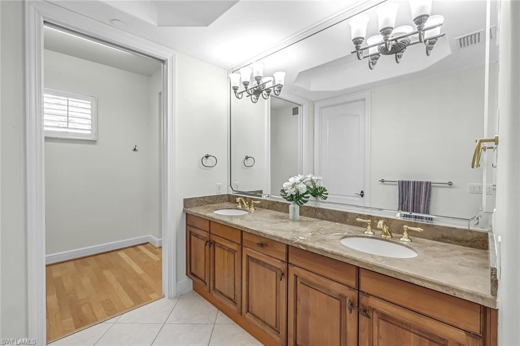 510 Avellino Isles Circle, Unit 2202 Naples, FL 34119 - Photo 14 of 35 a bathroom with a granite countertop sink and a mirror