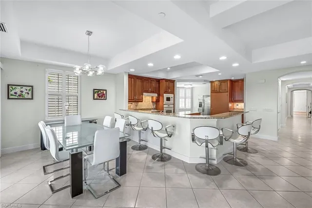 a living room with patio furniture and a dining table with kitchen view