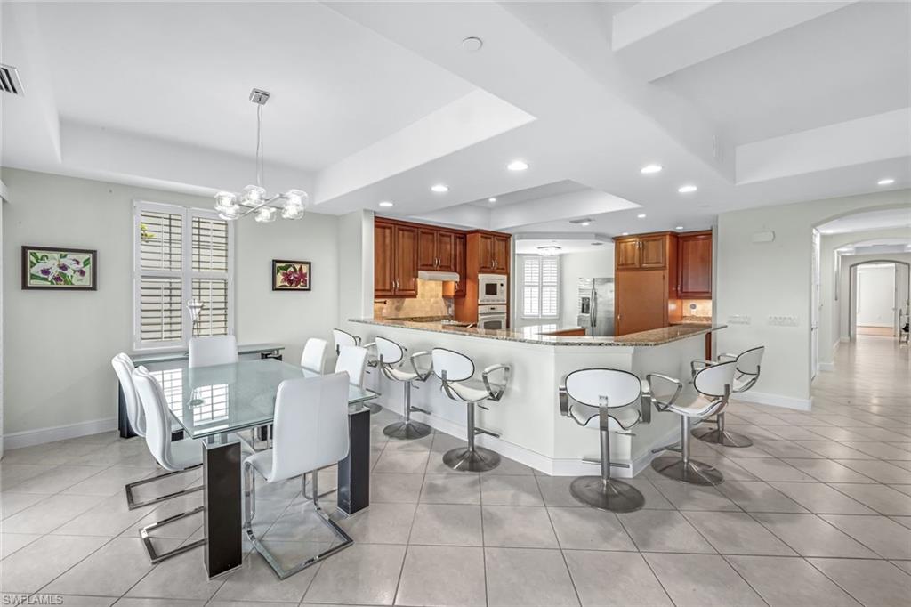 510 Avellino Isles Circle, Unit 2202 Naples, FL 34119 - Photo 7 of 35 a living room with patio furniture and a dining table with kitchen view