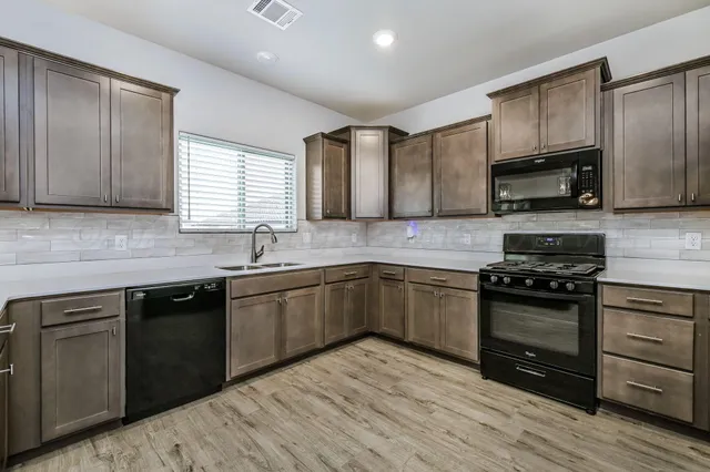 a kitchen with stainless steel appliances granite countertop wooden cabinets a stove a sink and dishwasher