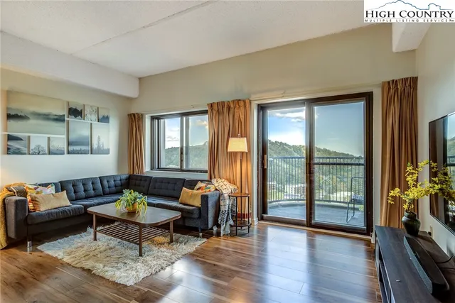 a living room with furniture a flat screen tv and a floor to ceiling window