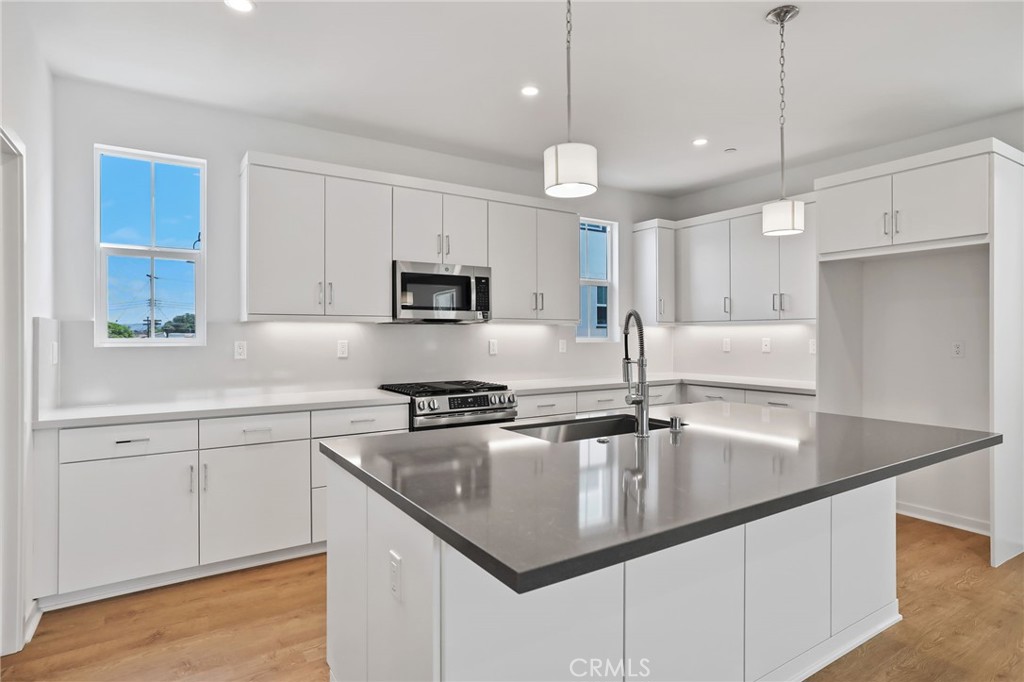139 Jessup Way Tustin, CA 92780 - Photo 11 of 31 a kitchen with kitchen island granite countertop a sink a counter space appliances and cabinets