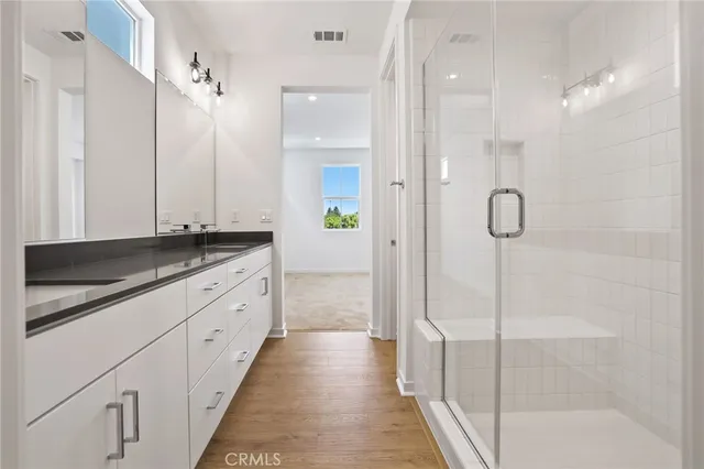 a bathroom with a granite countertop double vanity sink and mirror