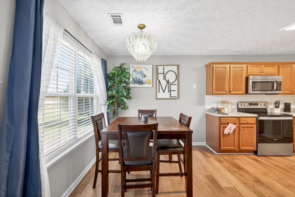 1501 Cardinal Lane Winder, GA 30680 - Photo 10 of 33 a dining room with wooden floor a chandelier a wooden table and chairs