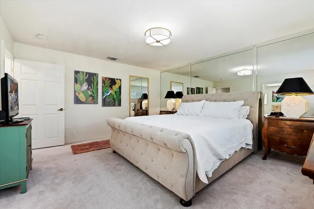 a spacious bedroom with a bed and a flat screen tv