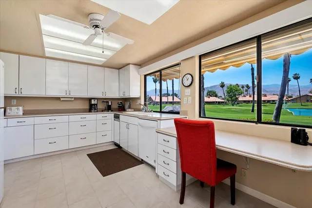 a kitchen with granite countertop a stove a sink dishwasher a dining table and chairs with wooden floor