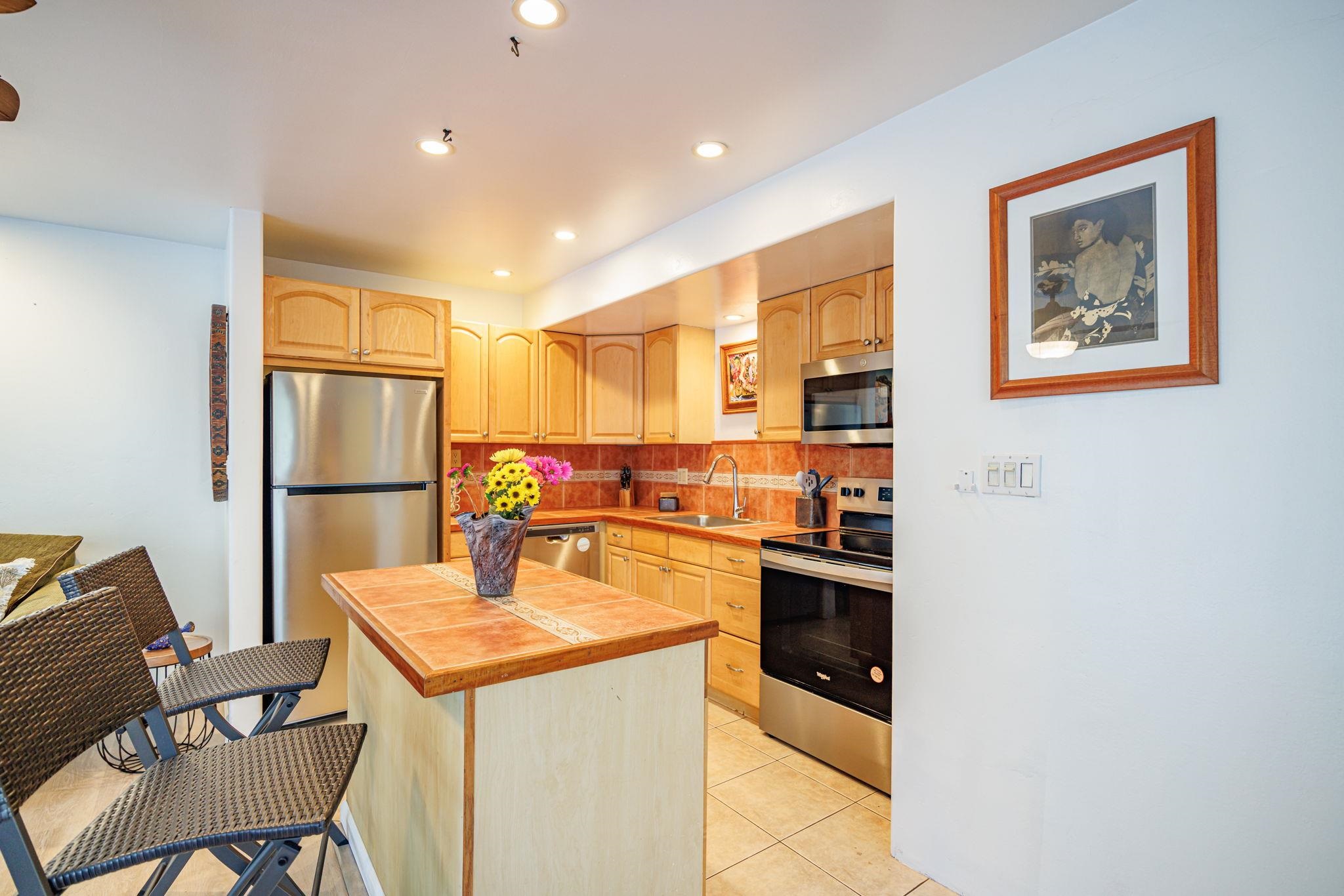 3559 Lower Honoapiilani Road, Unit 720 Lahaina, HI 96761 - Photo 13 of 31 a kitchen with stainless steel appliances granite countertop a refrigerator a stove a sink a dining table and chairs with wooden floor