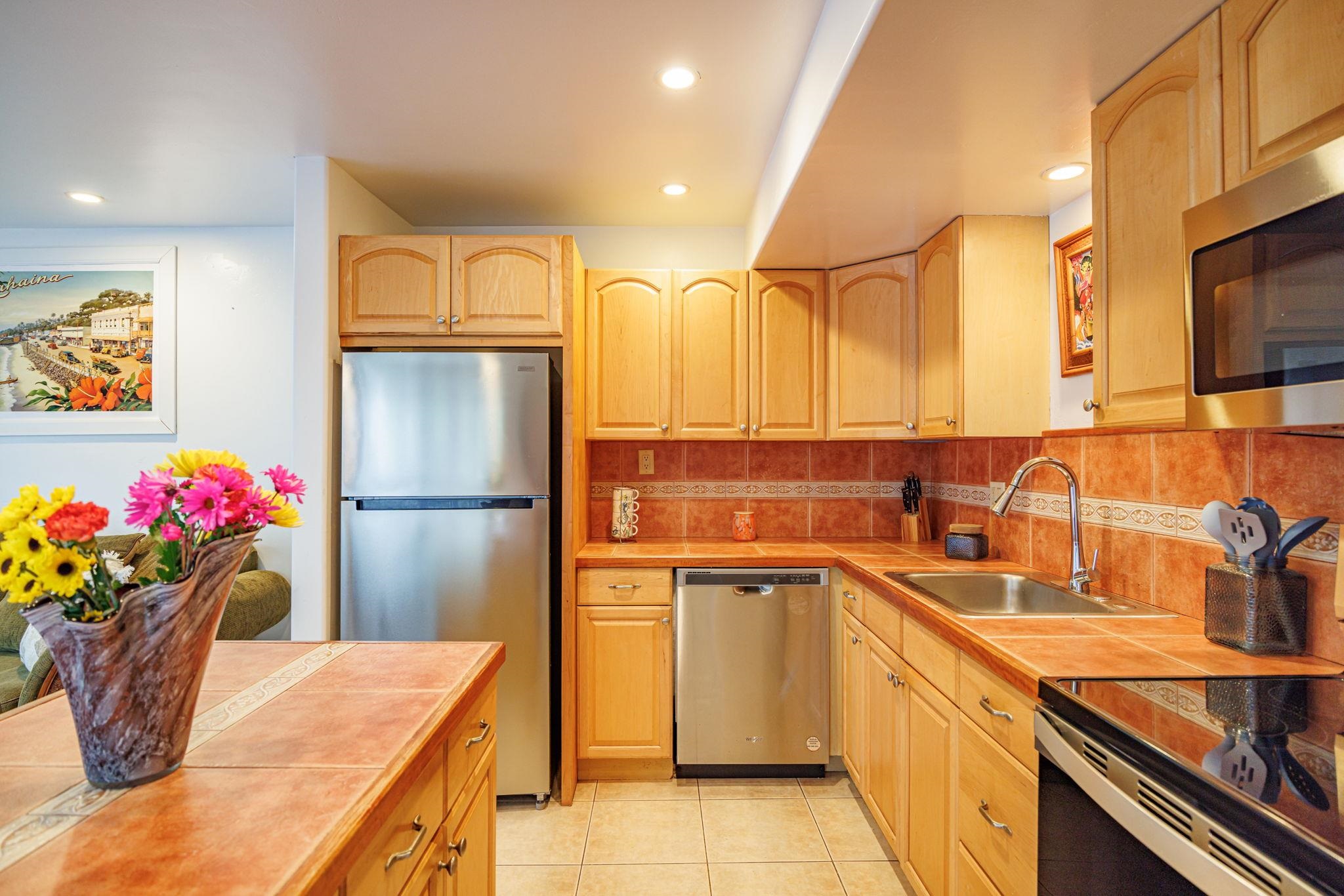 3559 Lower Honoapiilani Road, Unit 720 Lahaina, HI 96761 - Photo 16 of 31 a kitchen with stainless steel appliances granite countertop a sink refrigerator and microwave