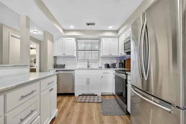 a kitchen with white cabinets stainless steel appliances and window