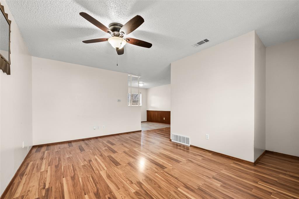 404 Vaden Avenue Everman, TX 76140 - Photo 4 of 16 an empty room with wooden floor and ceiling fan