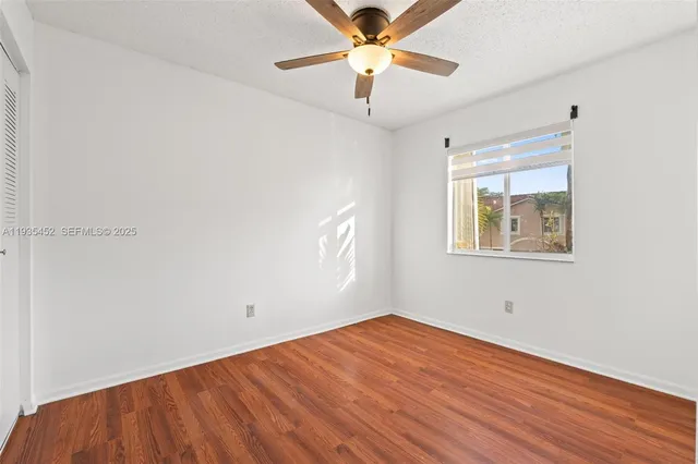 an empty room with a window and a ceiling fan