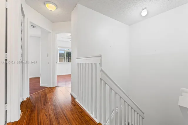 a view of a hallway with wooden floor and staircase