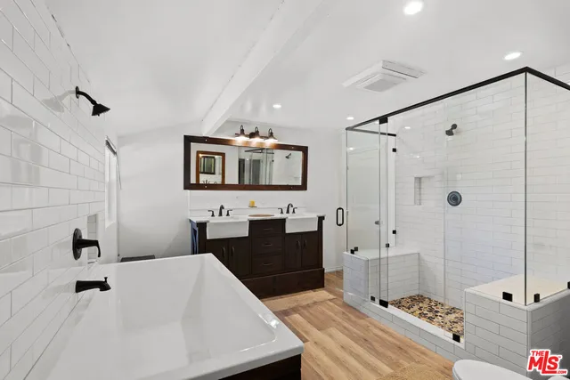 a bathroom with a double vanity sink a toilet a mirror and shower