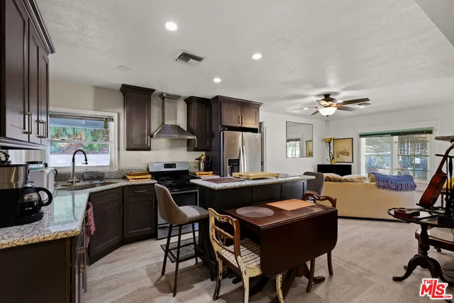 a kitchen with a stove a sink dishwasher a dining table and chairs with wooden floor