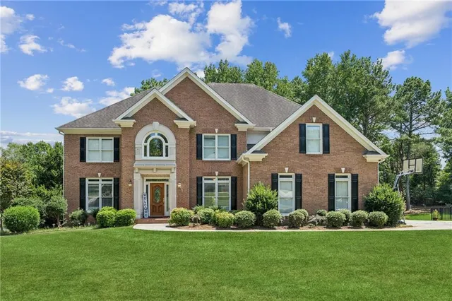 a front view of a house with a garden and yard