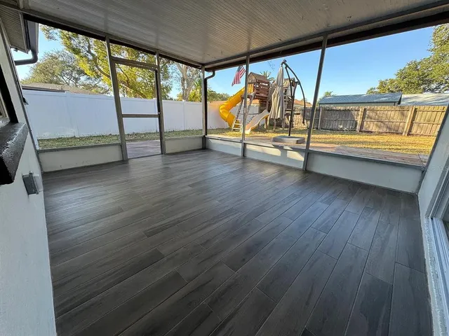 a view of an empty room with wooden floor and furniture