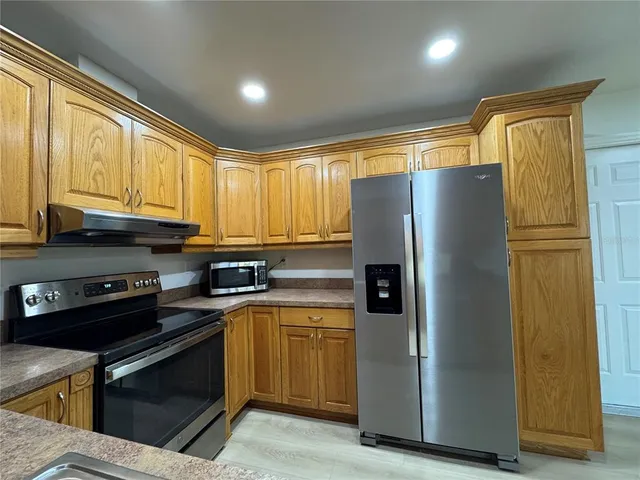 a kitchen with stainless steel appliances granite countertop a refrigerator a sink and a stove