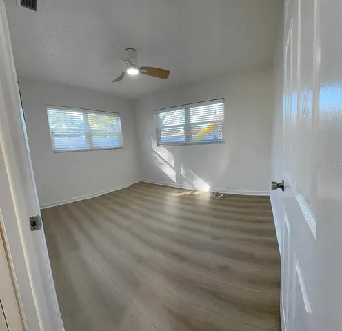 a view of empty room with wooden floor and fan