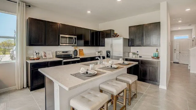 a kitchen with stainless steel appliances a stove a sink a microwave a refrigerator and cabinets