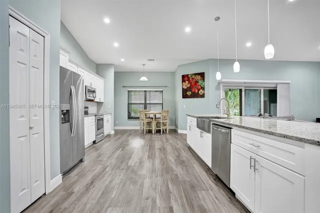 a large white kitchen with wooden floor and stainless steel appliances