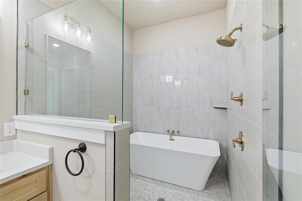 709 Anne Road Van Alstyne, TX 75495 - Photo 21 of 28 Bathroom featuring a freestanding tub, glass-enclosed shower, gold-toned plumbing fixtures, light wood-finish cabinetry, and a vanity with a white countertop