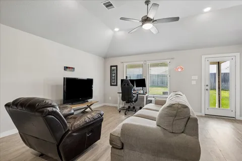 a living room with furniture a ceiling fan and a flat screen tv