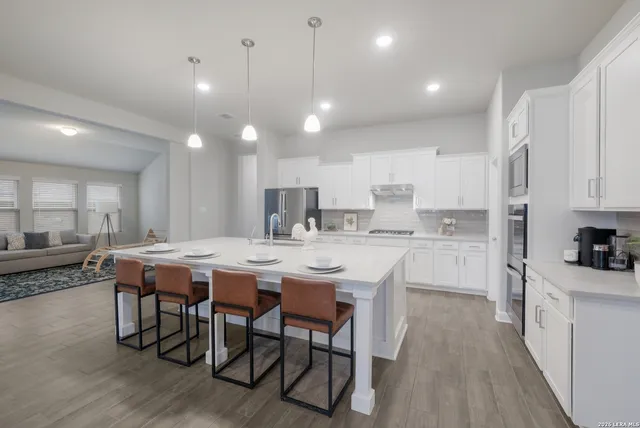 a kitchen with stainless steel appliances kitchen island granite countertop a table chairs sink and cabinets