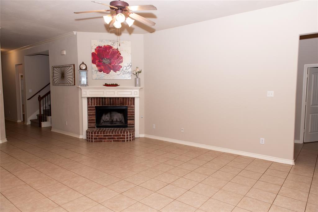 5125 Shelly Ray Road Fort Worth, TX 76244 - Photo 6 of 27 Unfurnished living room with a brick fireplace, light tile patterned floors, stairway, a ceiling fan, and crown molding