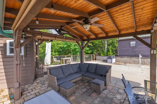 a roof deck with couches and wooden fence next to a yard