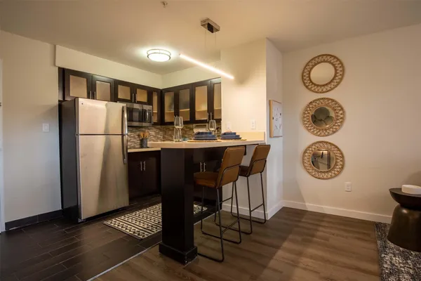 a kitchen with a refrigerator a microwave oven a sink and a dining table with chairs