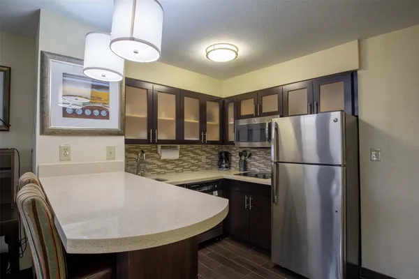 a kitchen with stainless steel appliances granite countertop a refrigerator a sink a stove and a dining table