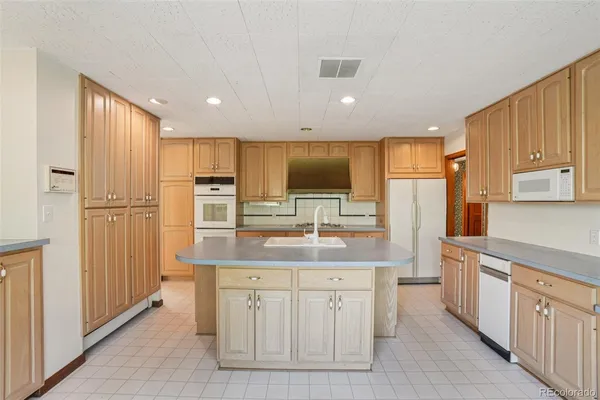 a kitchen with kitchen island granite countertop a sink refrigerator and cabinets