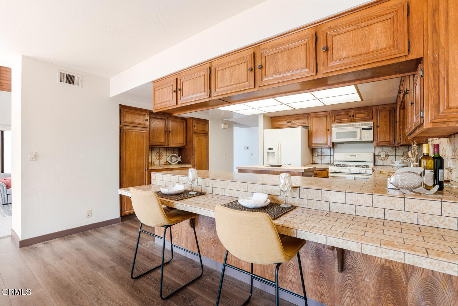 2101 Napoli Drive Oxnard, CA 93035 - Photo 16 of 50 a kitchen with stainless steel appliances kitchen island granite countertop a table chairs in it and a wooden floor