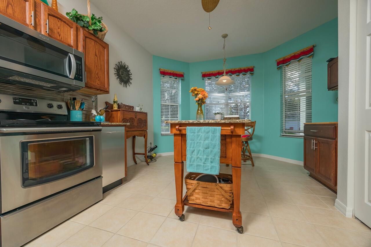 1041 Ridgewood Lane St. Augustine, FL 32086 - Photo 24 of 40 a kitchen with stainless steel appliances kitchen island granite countertop dining table and chairs