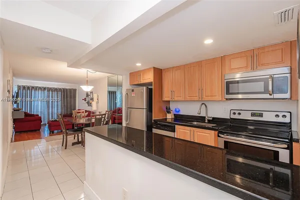 a kitchen with stainless steel appliances kitchen island granite countertop a stove a sink a refrigerator and cabinets
