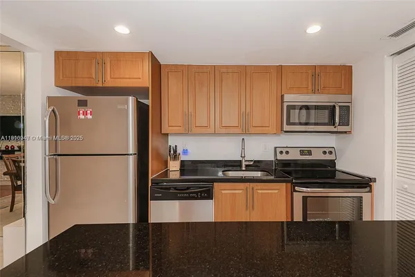 a kitchen with granite countertop a refrigerator and a stove top oven