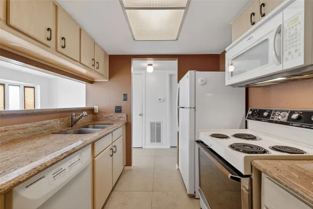 a kitchen with stainless steel appliances granite countertop a refrigerator a stove and a sink
