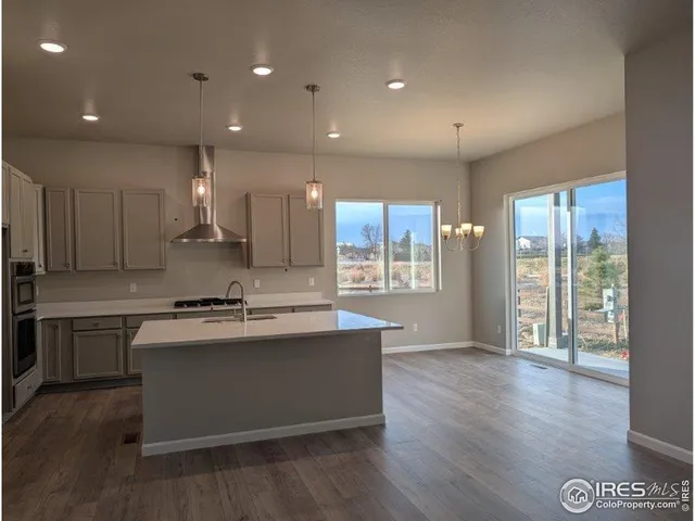 a large kitchen with stainless steel appliances granite countertop a stove a sink and a large refrigerator with wooden floor