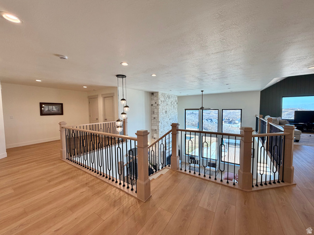 3626 Riverstone Road Mapleton, UT 84664 - Photo 23 of 58 Hallway with an upstairs landing, light wood finished floors, a textured ceiling, and plenty of natural light
