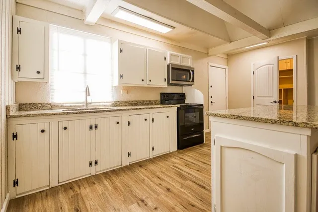 a kitchen with granite countertop white cabinets and white appliances