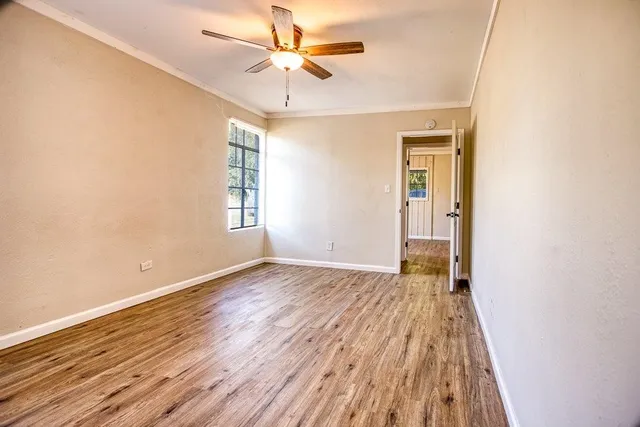 an empty room with wooden floor chandelier fan and closet area