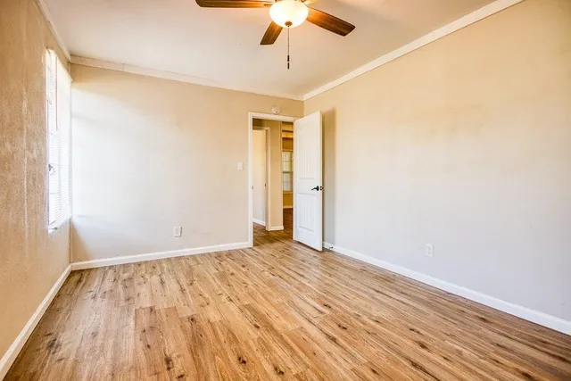 a view of empty room with wooden floor and fan