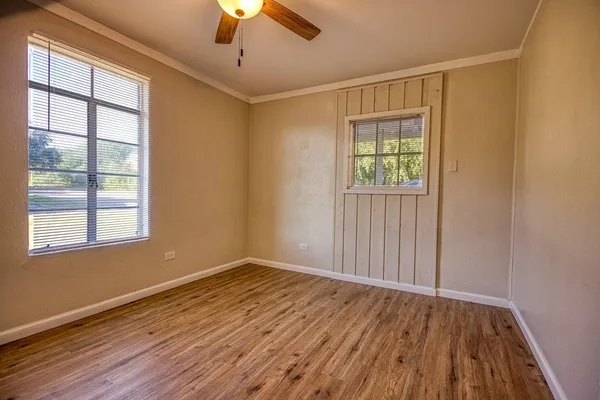 a view of an empty room with wooden floor and a window
