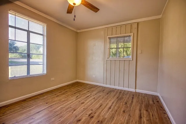 a view of an empty room with wooden floor and a window