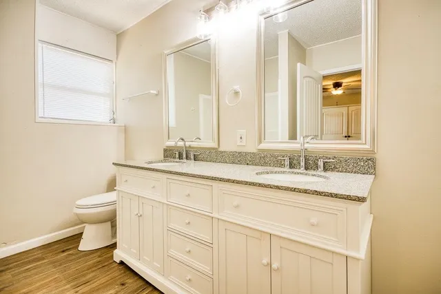 a bathroom with a granite countertop sink mirror and a toilet