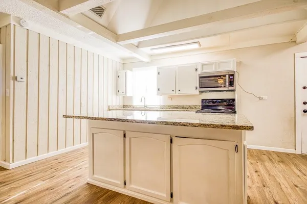 a kitchen with stainless steel appliances granite countertop a stove a sink and a microwave