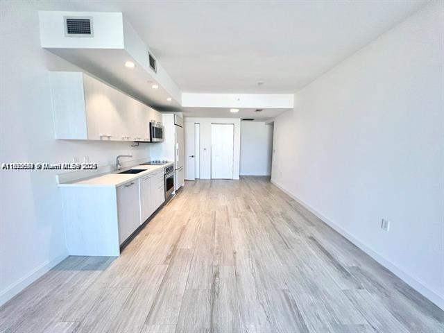 45 Southwest 9th Street, Unit 3009 Miami, FL 33130 - Photo 6 of 35 a view of a kitchen with wooden floor and stainless steel appliances